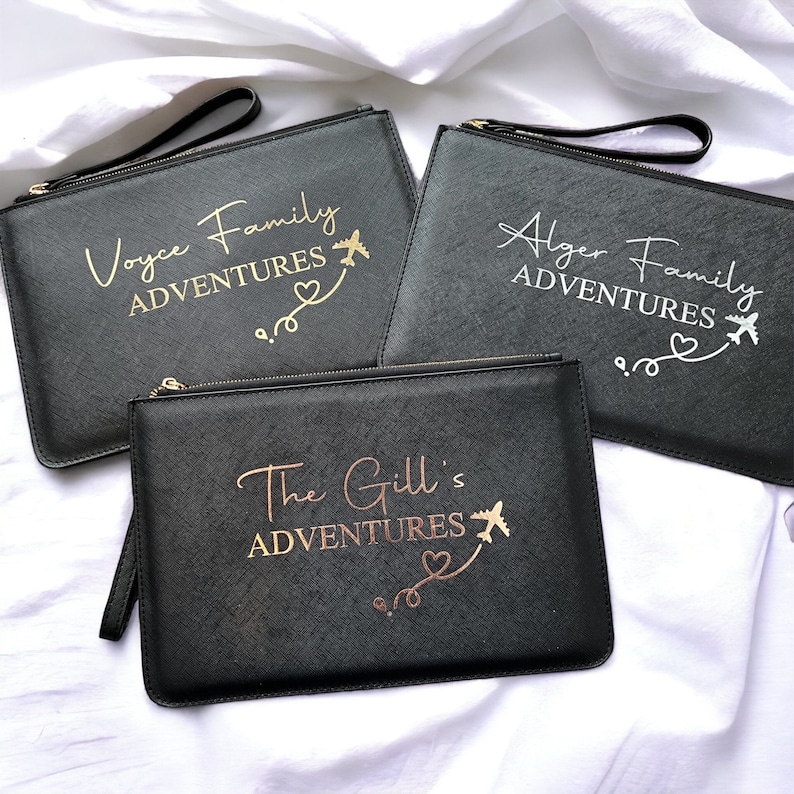 May include: Three black zippered pouches with gold lettering. The pouches are personalized with the text "Voyce Family Adventures", "Alger Family Adventures", and "The Gill's Adventures". Each pouch features a gold airplane and heart design.