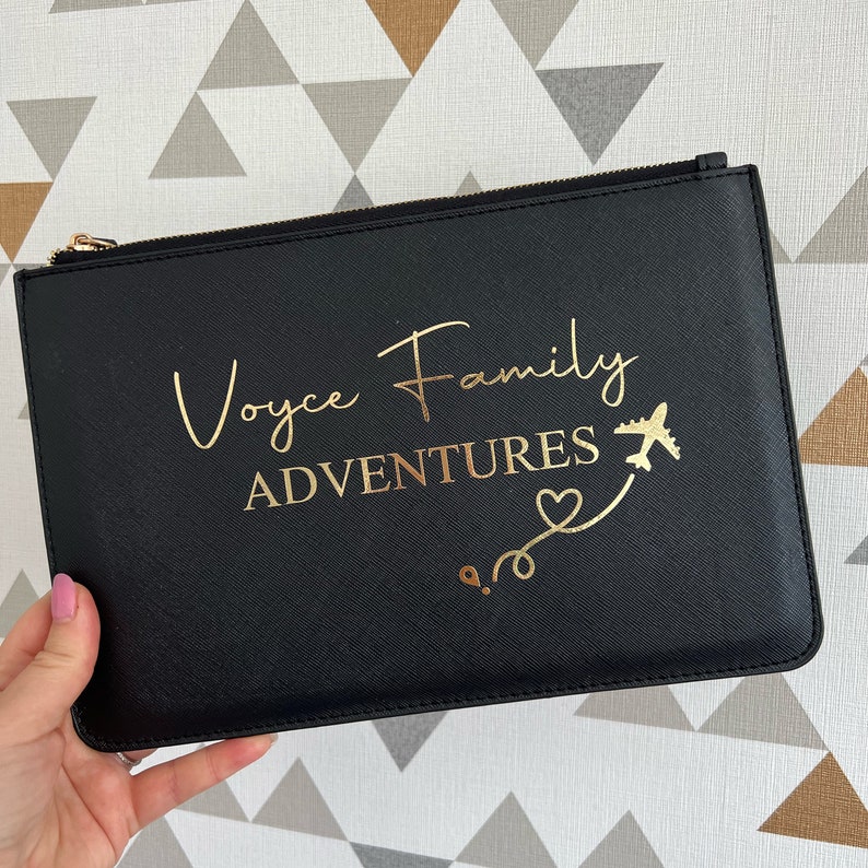 May include: Black zippered pouch with gold foil lettering that reads "Voyce Family Adventures" with a gold airplane and heart design.