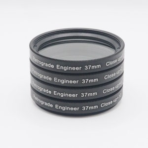 以下が含まれることがあります： 4つの黒いクローズアップレンズフィルターが積み重ねられています。各フィルターには、「Retrograde Engineer 37mm」と「Close up」の文字と倍率の数字が書かれています。