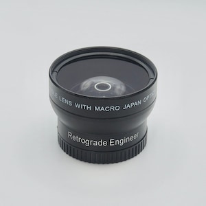 Puede incluir: Un objetivo de ojo de pez negro con el texto "Double Lens with Macro Japan Optics" y "Retrograde Engineer" impreso en él.