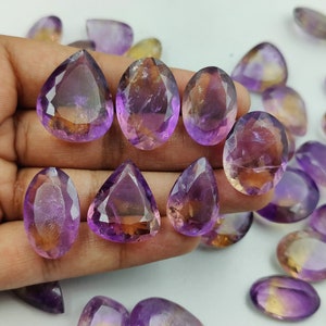 May include: A collection of amethyst and citrine gemstone drops, with a mix of purple and yellow hues. The stones are faceted and have a pear shape.