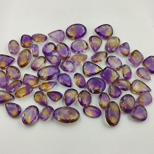 May include: A collection of amethyst and citrine gemstone drops, with a mix of purple and yellow hues. The stones are faceted and have a pear shape.