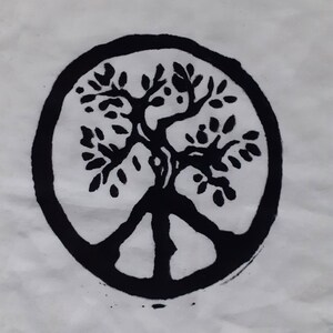 May include: Black and white illustration of a tree of life inside a circle. The tree has a peace sign at the base of its trunk.