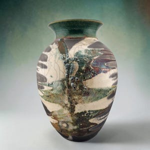 May include: A ceramic vase with a flared rim, featuring a dark green glazed neck and a body decorated with a crackle pattern in cream, black, and metallic green tones. The surface displays a textured, mottled finish with organic, layered glaze effects.