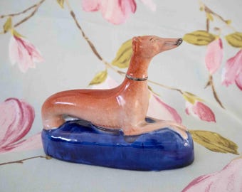 Glorious 19th century Staffordshire quill or pen holder: recumbent greyhound, gilt lined base