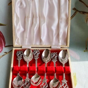 Peut inclure: Un ensemble de huit cuillères à café en argent avec des manches ornés dans une boîte blanche avec une doublure en velours rouge.