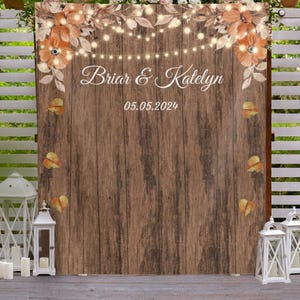 May include: A rustic wooden backdrop with a floral design and string lights. The text "Briar & Katelyn" and the date "05.05.2024" are printed on the backdrop.