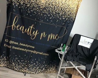 May include: Black backdrop with gold glitter and the text "beauty n me - BEAUTY THAT'S WITHIN YOU" with contact information below. A black makeup chair with a white logo that says "beauty n me" is in the foreground.