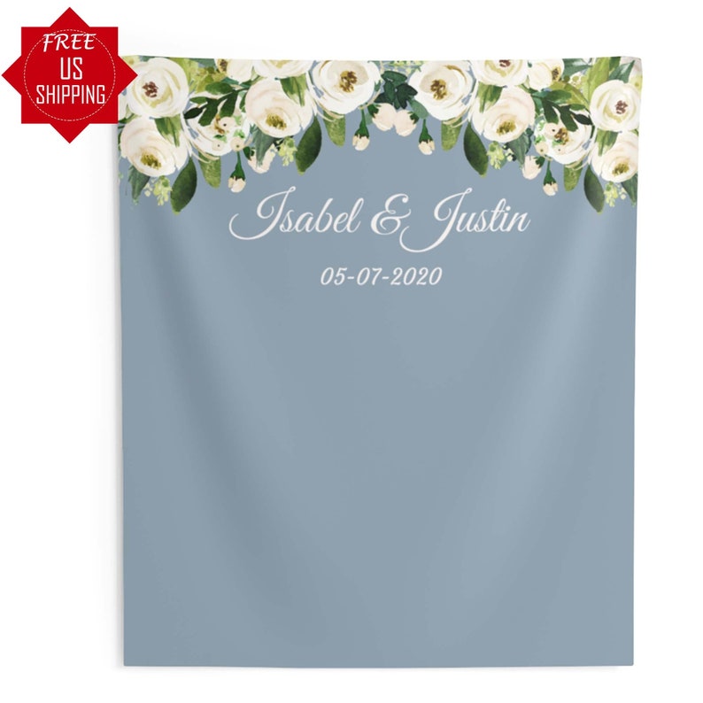 May include: A light blue backdrop with a white floral garland at the top. The text "Isabel & Justin" and the date "05-07-2020" are printed in white below the garland.