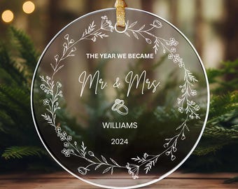 Pode incluir: Ornamento redondo transparente com um design floral branco e o texto "The year we became Mr. & Mrs. Williams 2024".