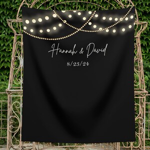 May include: Black backdrop with white string lights and the text "Hannah & David" and "8/23/24" in white.