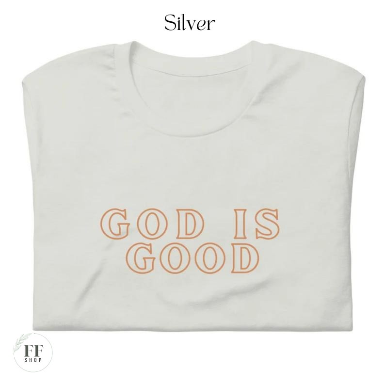 Op de afbeelding: Een wit T-shirt met de tekst "GOD IS GOOD" in oranje.