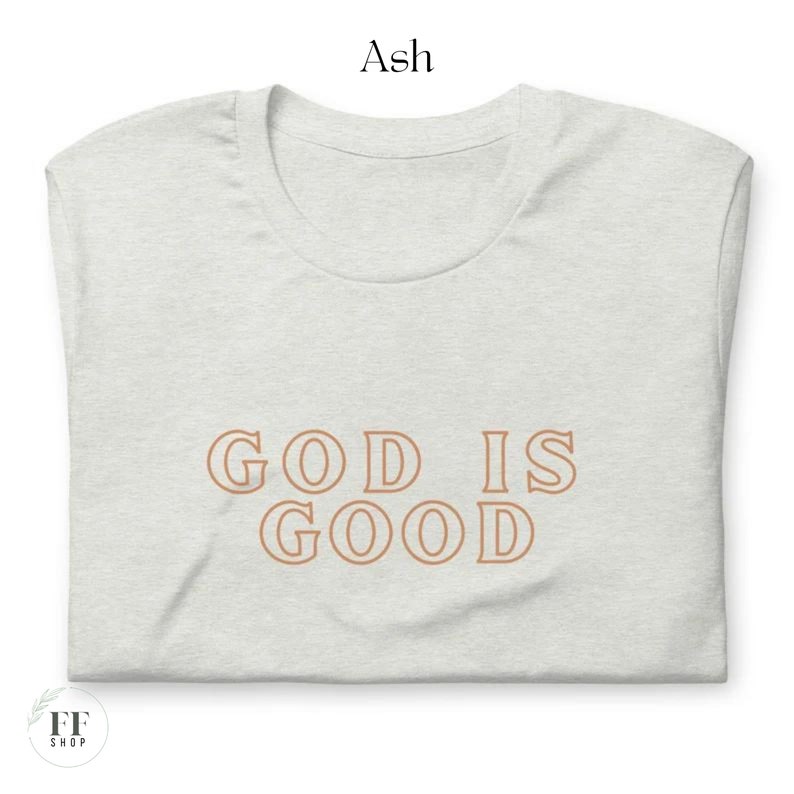 Op de afbeelding: Een lichtgrijs T-shirt met de tekst "GOD IS GOOD" in bruin gedrukt op de voorkant.