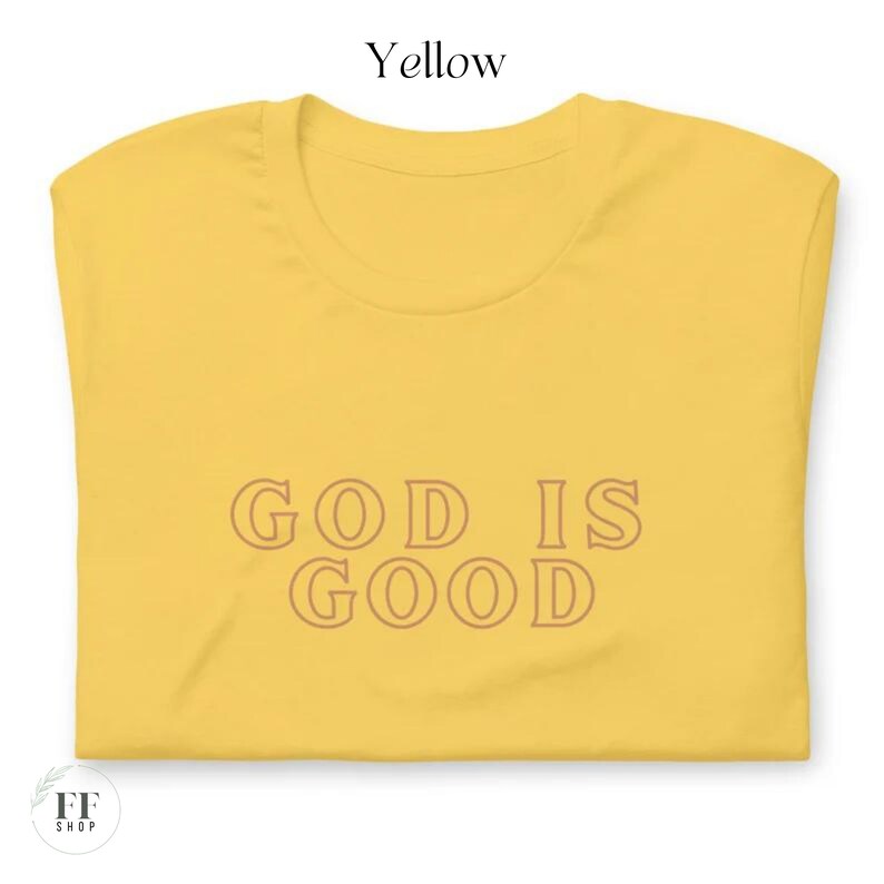 Op de afbeelding: Geel T-shirt met de tekst "GOD IS GOOD" gedrukt in een bruine omtrek.