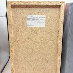 May include: The back panel of a rectangular Sony speaker system, model SS-CNEZ3, featuring a light brown particle board finish. A white label displays technical specifications including rated impedance of 6 ohms and serial number 8 373 417.