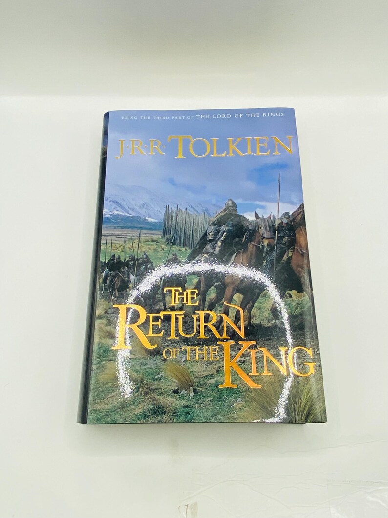 May include: A hardcover book titled "The Return of the King" by J.R.R. Tolkien. The cover features a painting of riders on horseback, with a mountain range in the background. The title is in gold lettering.