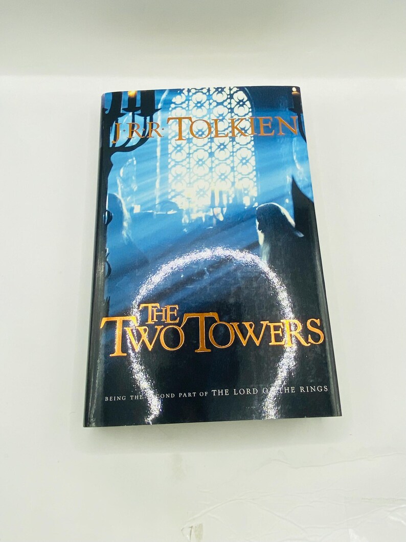 May include: A copy of "The Two Towers" by J.R.R. Tolkien, the second part of "The Lord of the Rings." The book cover features a blue and white illustration with gold lettering. The title is prominently displayed.