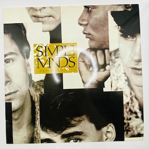Peut inclure: Pochette de l'album "Once Upon a Time" de Simple Minds. La couverture présente un collage d'images en noir et blanc des visages des membres du groupe. Le titre de l'album et le nom du groupe sont dans un encadré jaune et or.