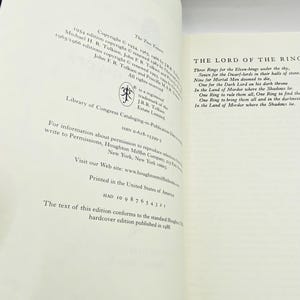 May include: Open book pages with text from "The Lord of the Rings" by J.R.R. Tolkien. The left page shows copyright information, while the right page displays the poem about the rings. The book is printed in the United States.