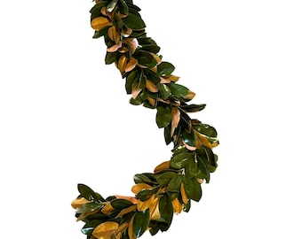 Puede incluir: Una larga guirlanda de hojas de magnolia en tonos verdes y dorados. Las hojas están dispuestas en un patrón fluido en forma de S.