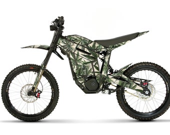 May include: An electric dirt bike with a green and white cannabis leaf pattern. The bike has black tires, a black frame, and a black seat. The front and rear wheels have disc brakes. The bike is designed for off-road use.