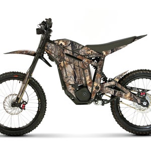May include: An electric dirt bike featuring a camouflage design. The bike has black tyres, a black seat, and a black frame. The camouflage pattern incorporates shades of brown, green, and tan. It has disc brakes and a front mudguard.