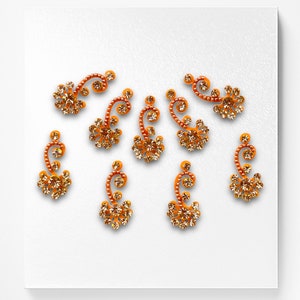 May include: Set of eight gold and orange jeweled body stickers in a paisley design.