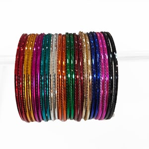 May include: A stack of colourful metal bangles with a shiny finish. The bangles are arranged in a rainbow pattern, with red, orange, yellow, green, blue, indigo, and violet.