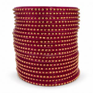 May include: A stack of deep magenta bangles, each featuring a single row of small, raised gold-toned beads encircling the outer surface. The bangles are uniform in colour and design, creating a cylindrical shape with a smooth, glossy finish.