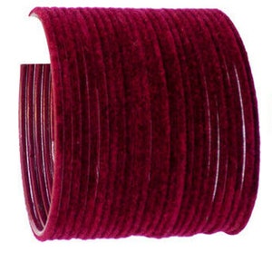Puede incluir: Un conjunto de pulseras de color rojo intenso, que muestran una textura rica y aterciopelada. Las pulseras están dispuestas en forma curva, revelando su forma circular. El color es un rojo vibrante y saturado, perfecto para añadir un toque de color.