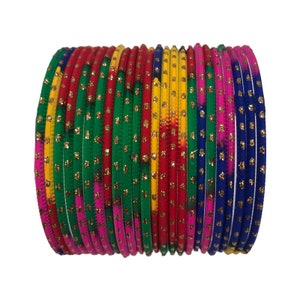 Può includere: Un gruppo di braccialetti colorati nei toni del rosso, verde, giallo, rosa e blu. Ogni braccialetto è adornato con dettagli glitterati dorati. I braccialetti sono impilati, creando un'esposizione vibrante e accattivante.