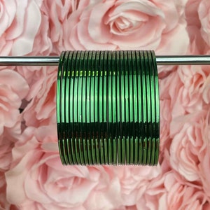 May include: A stack of green metal bangles. The bangles are shiny and have a slight metallic sheen.