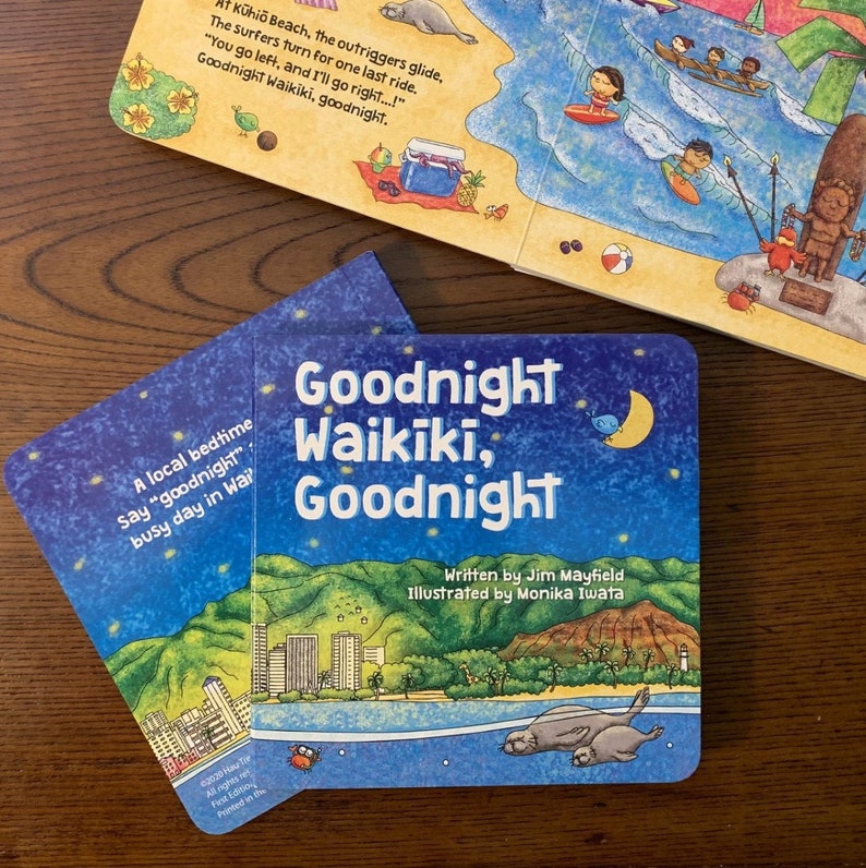 May include: A blue children's book with the title "Goodnight Waikiki, Goodnight" on the cover. The cover features a nighttime scene with a crescent moon, stars, and a cityscape with palm trees. The book is written by Jim Mayfield and illustrated by Monika Iwata.