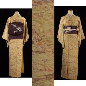 以下が含まれることがあります： 金と茶色の伝統的な日本の着物2着と、お揃いの生地パネル。着物は花柄と風景柄で、濃い茶色の帯ベルトが付いています。帯ベルトは扇のデザインです。