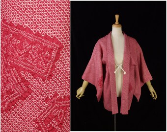Puede incluir: Un kimono japonés de color rosa y blanco con un cinturón blanco. El kimono está hecho de una tela suave y texturizada y tiene un corte holgado.