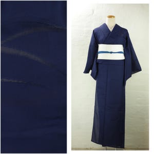 May include: A navy blue kimono, displayed on a mannequin, with a white obi and a blue accent. The fabric has a subtle texture. The image also shows a close-up of the fabric.