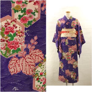 Op de afbeelding: Een paarse kimono met een bloemenpatroon. De kimono heeft een geometrisch ontwerp met roze, witte en groene bloemen. De kimono wordt gedragen door een mannequin.