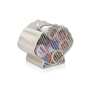 May include: A white, seashell-shaped coffee pod holder with a metal mesh front. The holder is filled with various coffee pods. The holder has a distressed, weathered finish, and a small compartment for additional pods.