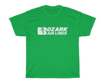 以下が含まれることがあります： 白いロゴに「OZARK AIR LINES」とスタイリッシュな鳥のデザインが施された緑色のTシャツです。