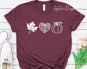 May include: A maroon t-shirt with a white graphic design of a leaf, heart, and pumpkin. The text "Joy Sun Designs" is visible in the top right corner of the image.