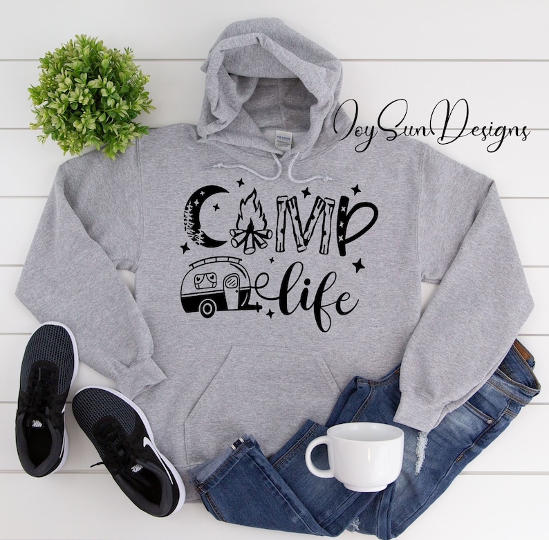 Pu&ograve; includere: Felpa con cappuccio grigia con il testo "Camp life" in lettere nere. Il design include un fal&ograve;, una luna crescente, stelle e un camper.