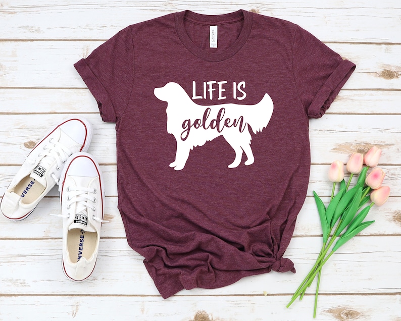 May include: A maroon t-shirt with a white silhouette of a golden retriever and the text "Life is golden".