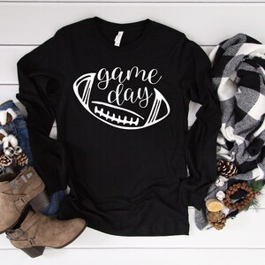 May include: Black long-sleeved shirt with the text "game day" and a white outline of a football.