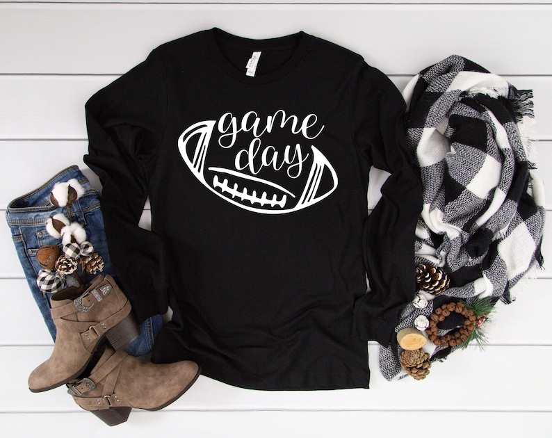 May include: Black long-sleeved shirt with the text "game day" and a white outline of a football.