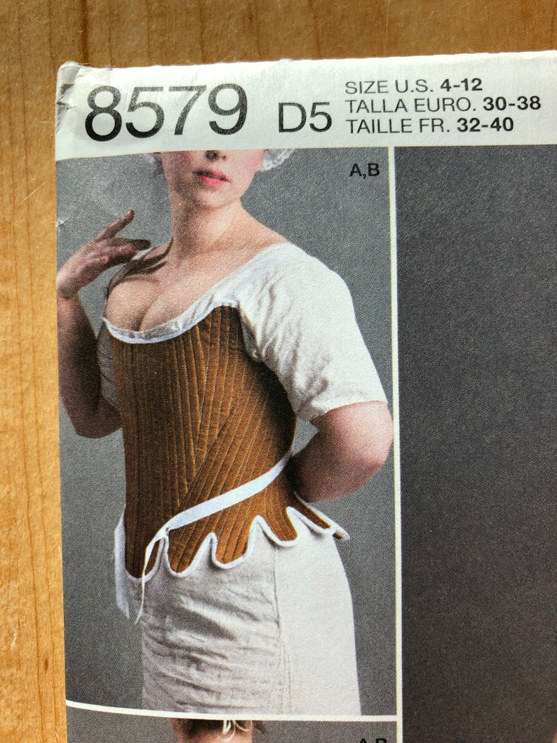 Pu&ograve; includere: Un cartamodello per un corsetto marrone e bianco con un bordo a festoni. Il numero del cartamodello &egrave; 8579 D5. La gamma di taglie &egrave; US 4-12, Euro 30-38 e Francese 32-40.