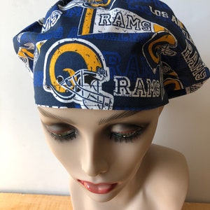 May include: A blue and yellow patterned scrub hat with the Los Angeles Rams logo and the word "RAMS" repeated throughout the design.
