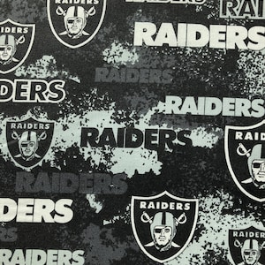May include: Black and white fabric with a repeated pattern of the Las Vegas Raiders logo and the word "RAIDERS".