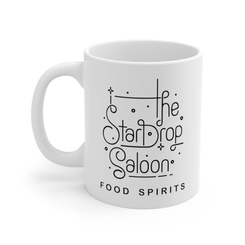 May include: White ceramic mug with a black design that reads "The Star Drop Saloon" and "Food Spirits".