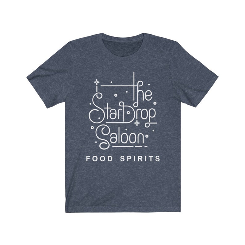 May include: A navy blue t-shirt with white text that reads "The StarDrop Saloon" in a stylized font. Below the name, the words "FOOD SPIRITS" are printed in a smaller font. The shirt has short sleeves and a crew neck.