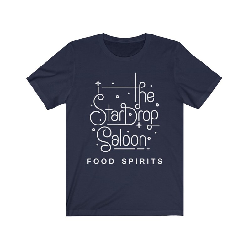 May include: Navy blue t-shirt with the white text "The StarDrop Saloon" in a decorative font, with the words "FOOD SPIRITS" below. The shirt has short sleeves and a crew neck.